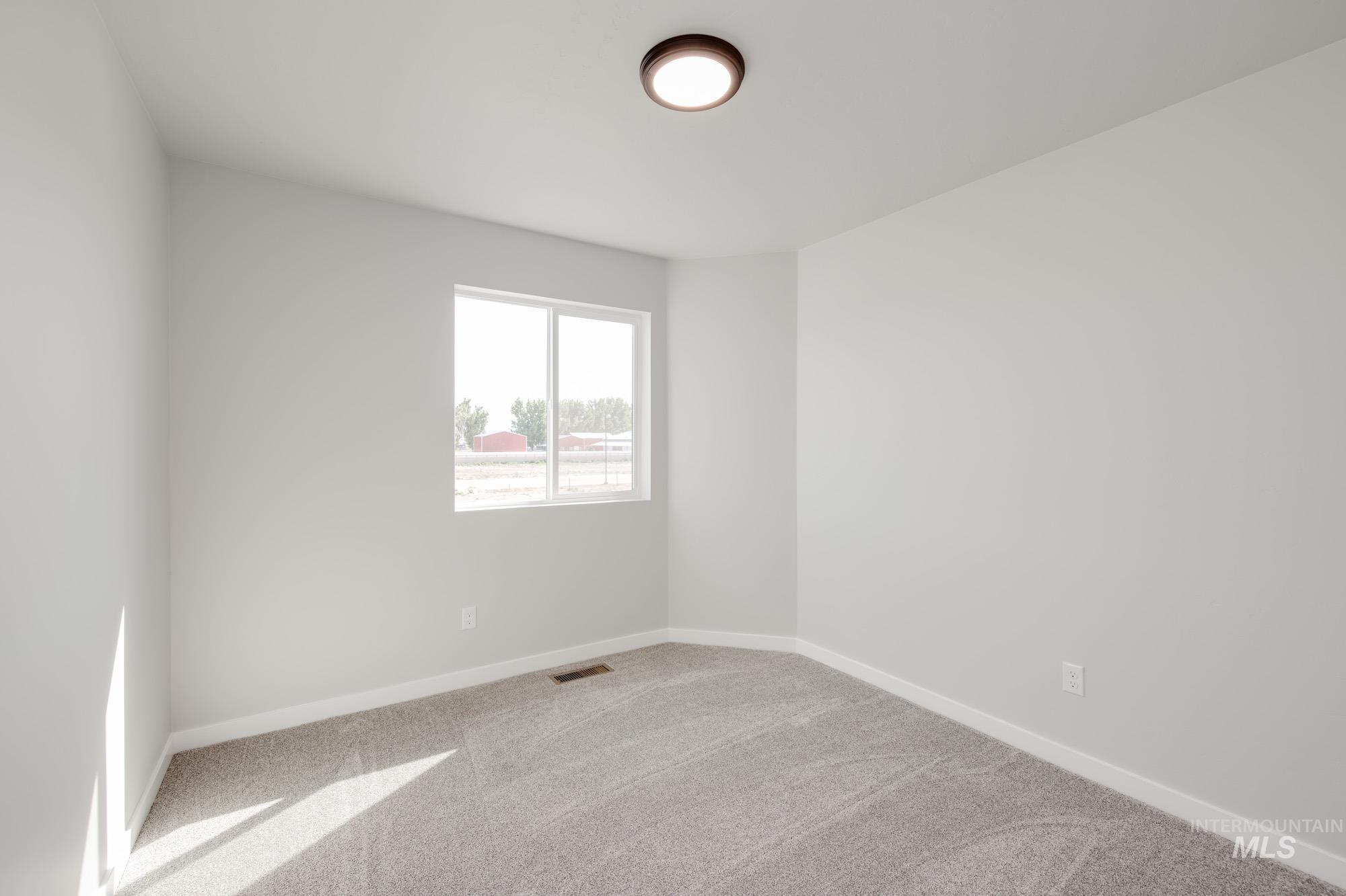 Spare room featuring carpet flooring and baseboards