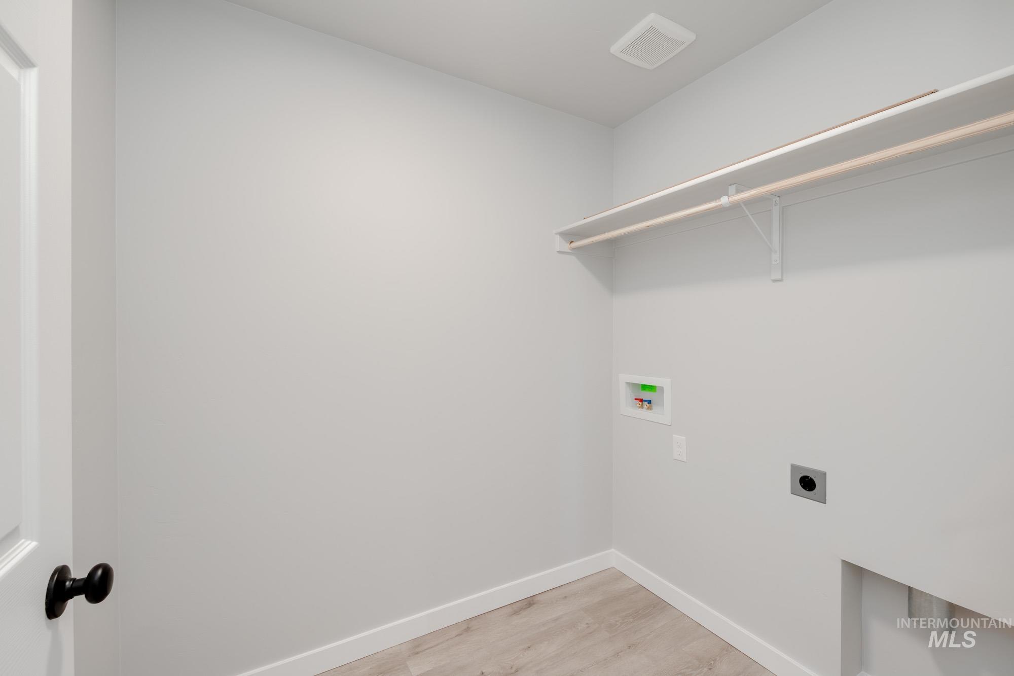 Washroom with light wood-style floors, hookup for a washing machine, and electric dryer hookup