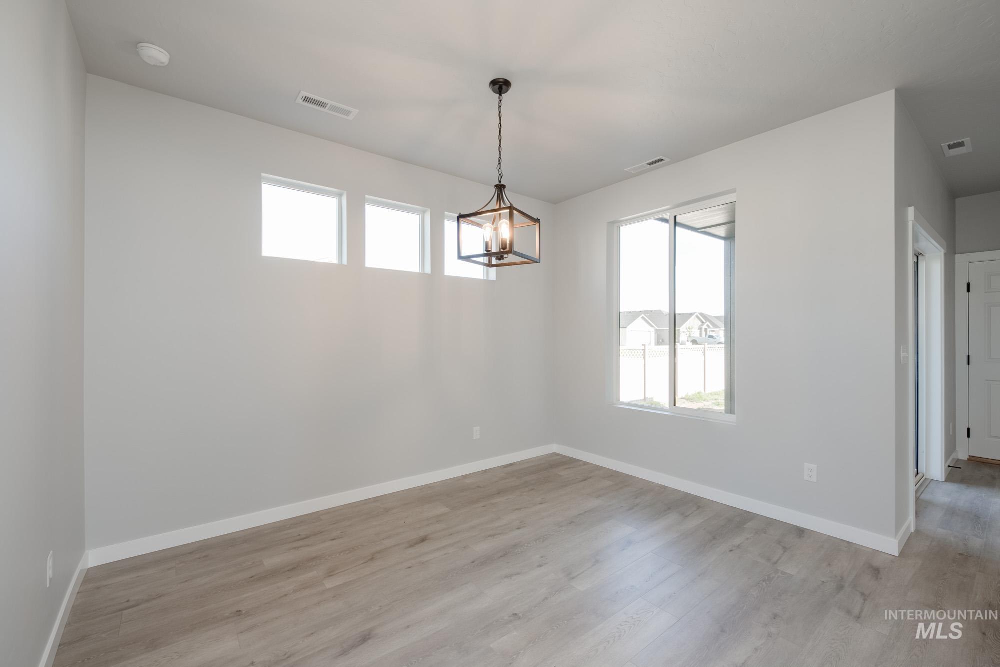 Unfurnished dining area with plenty of natural light, light wood-type flooring, and a chandelier
