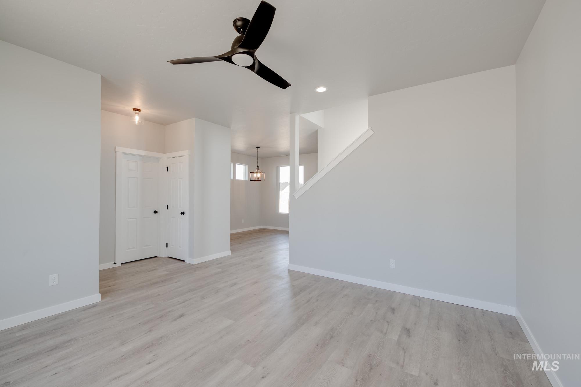Unfurnished living room featuring light wood finished floors, a chandelier, ceiling fan, and recessed lighting