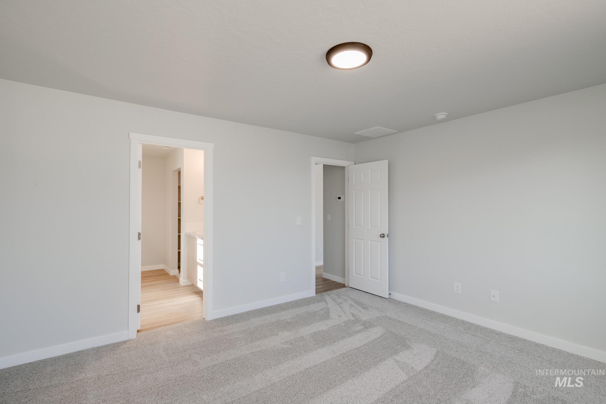 Unfurnished bedroom with light colored carpet and connected bathroom