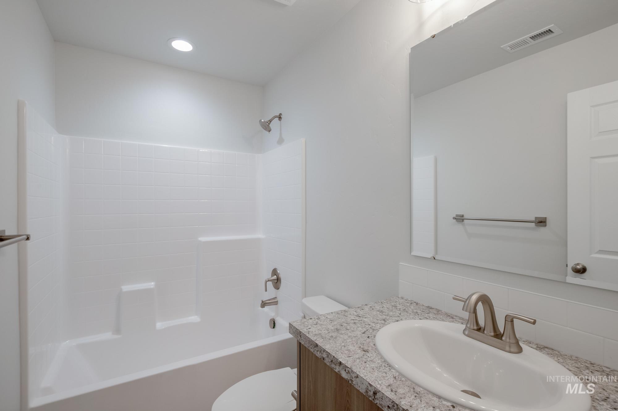 Bathroom with bathing tub / shower combination, vanity, and backsplash