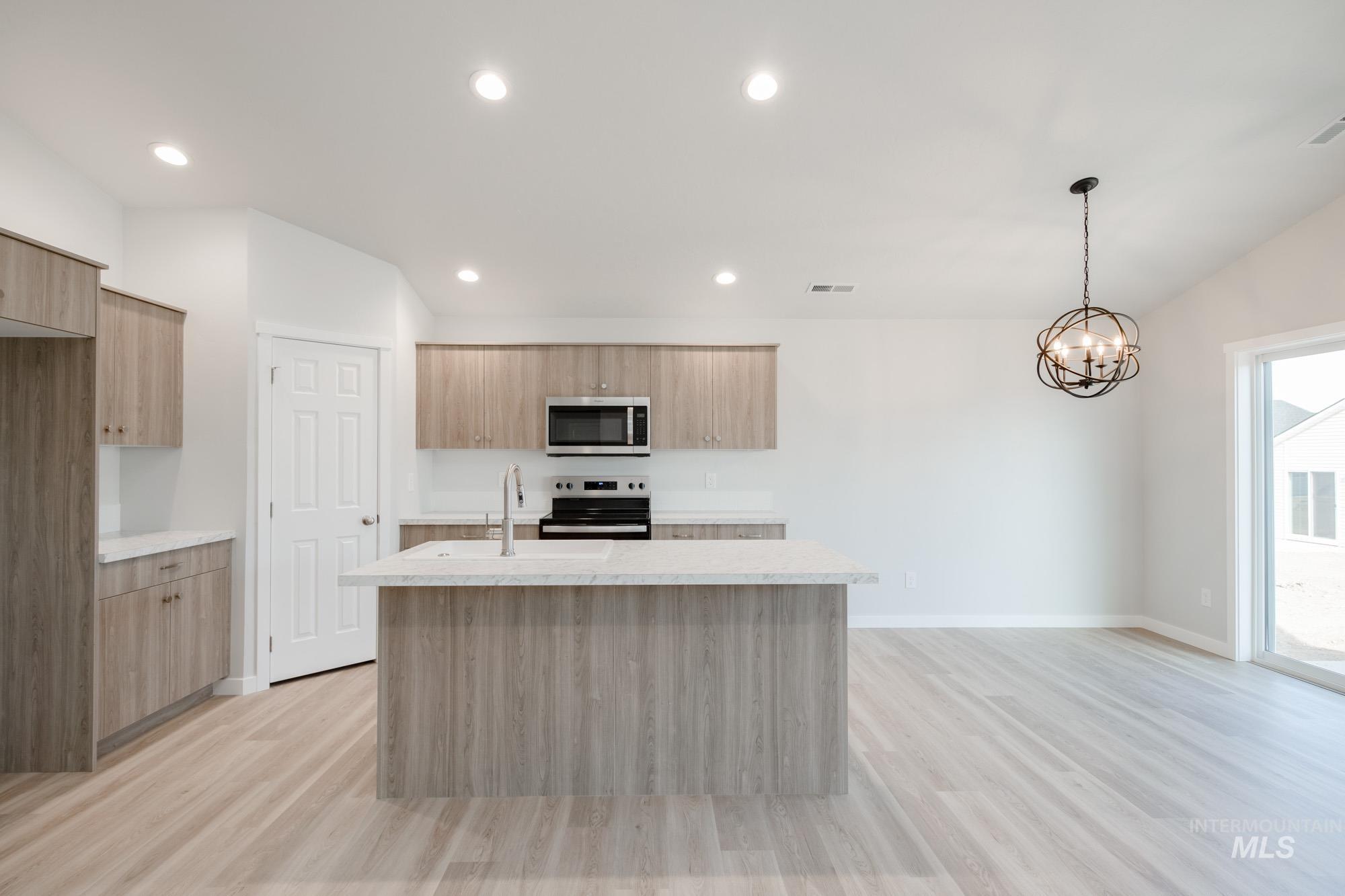 Kitchen featuring pendant lighting, a center island with sink, appliances with stainless steel finishes, light wood-style flooring, and recessed lighting