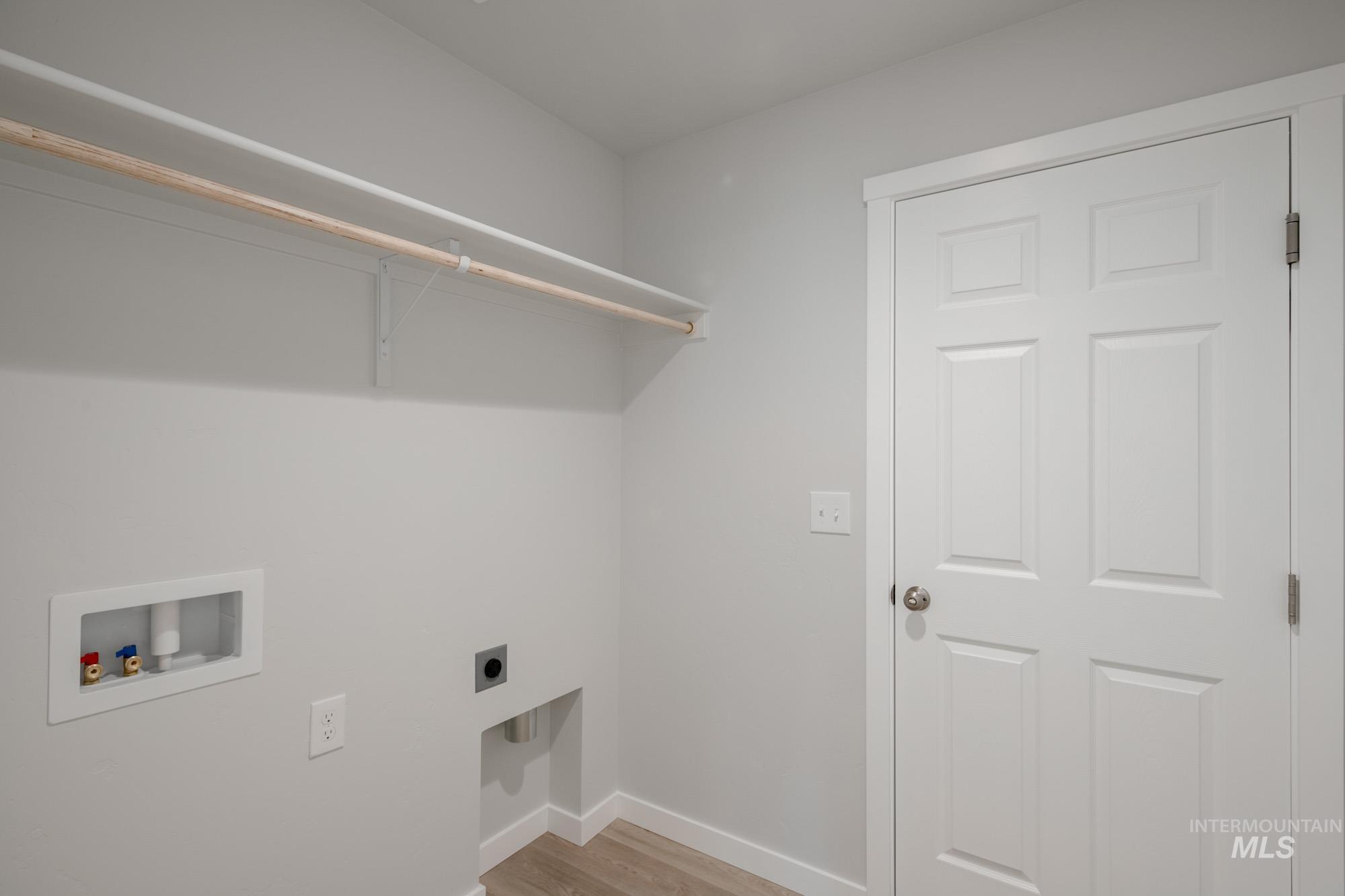 Laundry area with light wood-type flooring, electric dryer hookup, and hookup for a washing machine