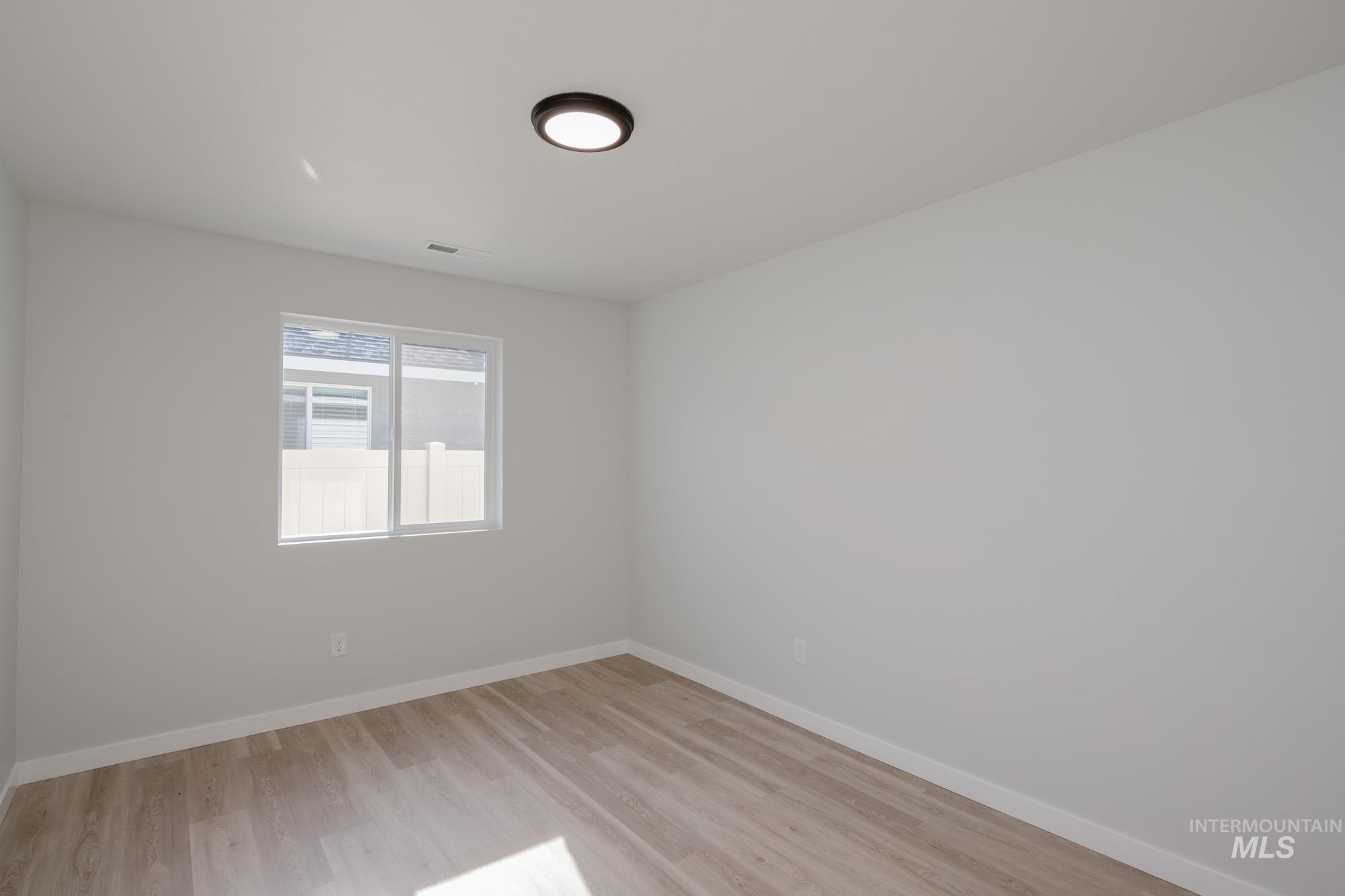 Unfurnished room with light wood finished floors and baseboards