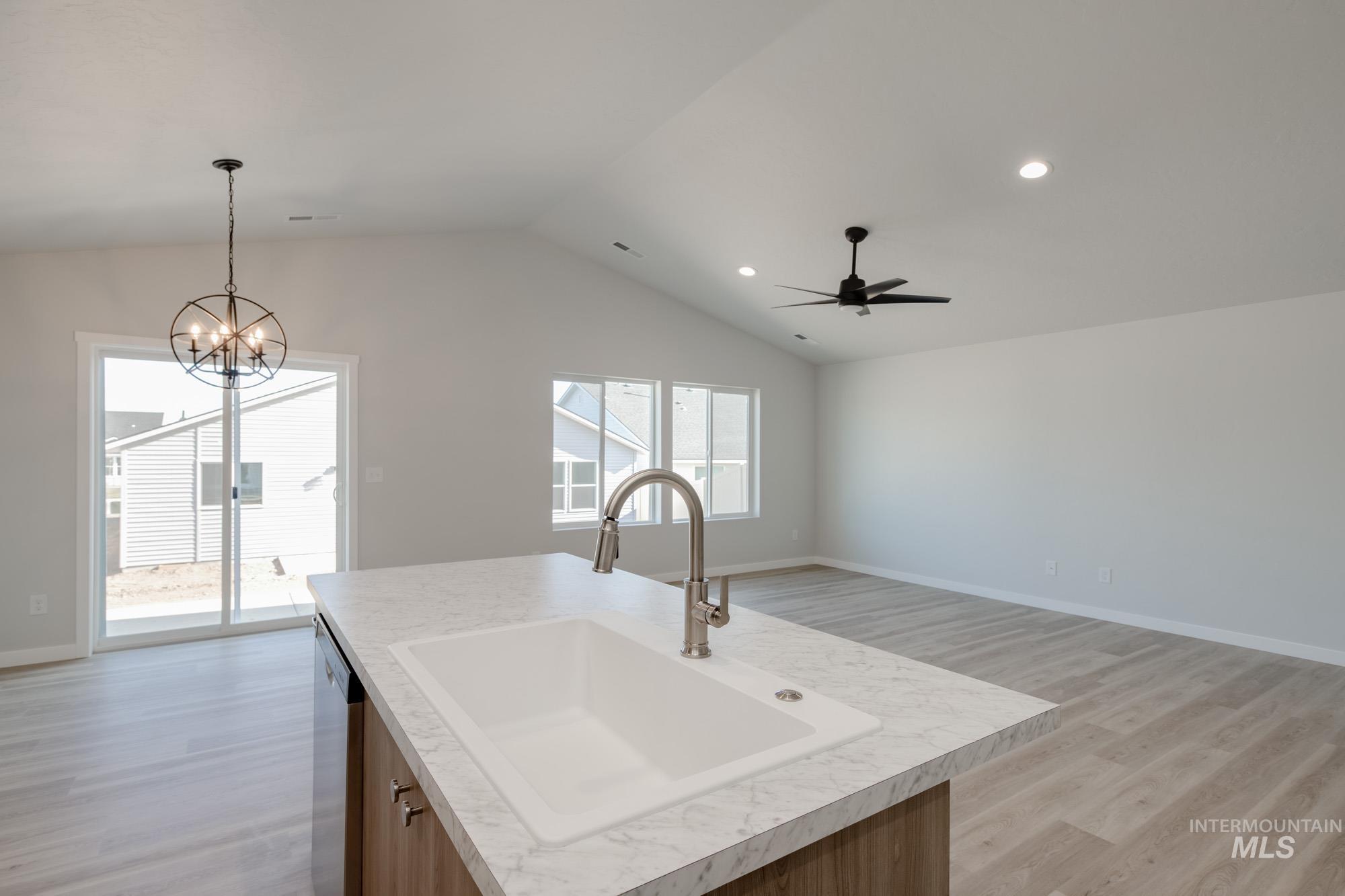 Kitchen featuring light wood-type flooring, light countertops, a kitchen island with sink, open floor plan, and brown cabinets