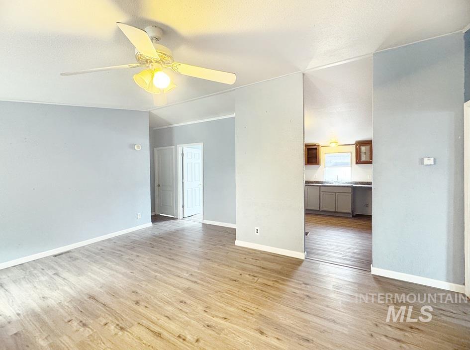 Spare room featuring light wood-style floors, a textured ceiling, and a ceiling fan
