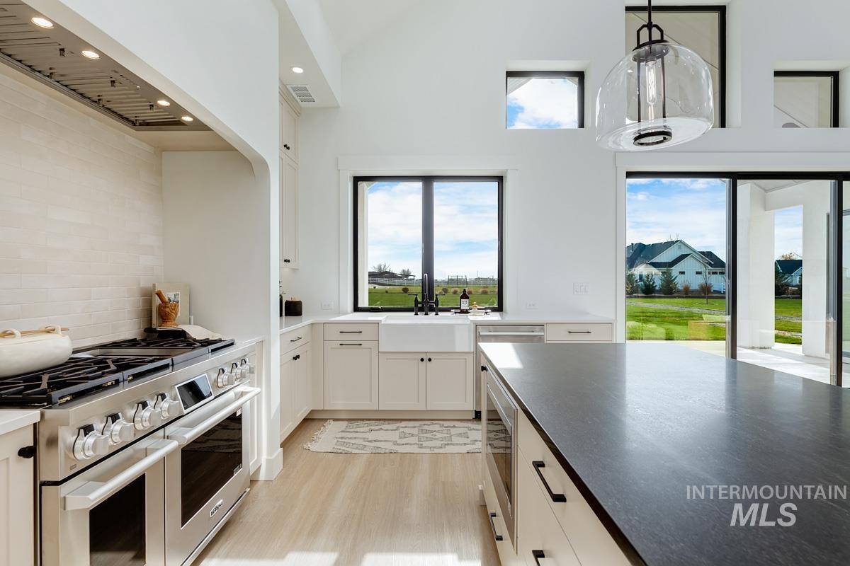 Kitchen featuring appliances with stainless steel finishes, decorative light fixtures, white cabinets, light wood-style flooring, and recessed lighting