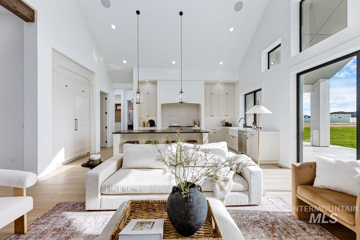 Living area featuring high vaulted ceiling, light wood-style flooring, and recessed lighting