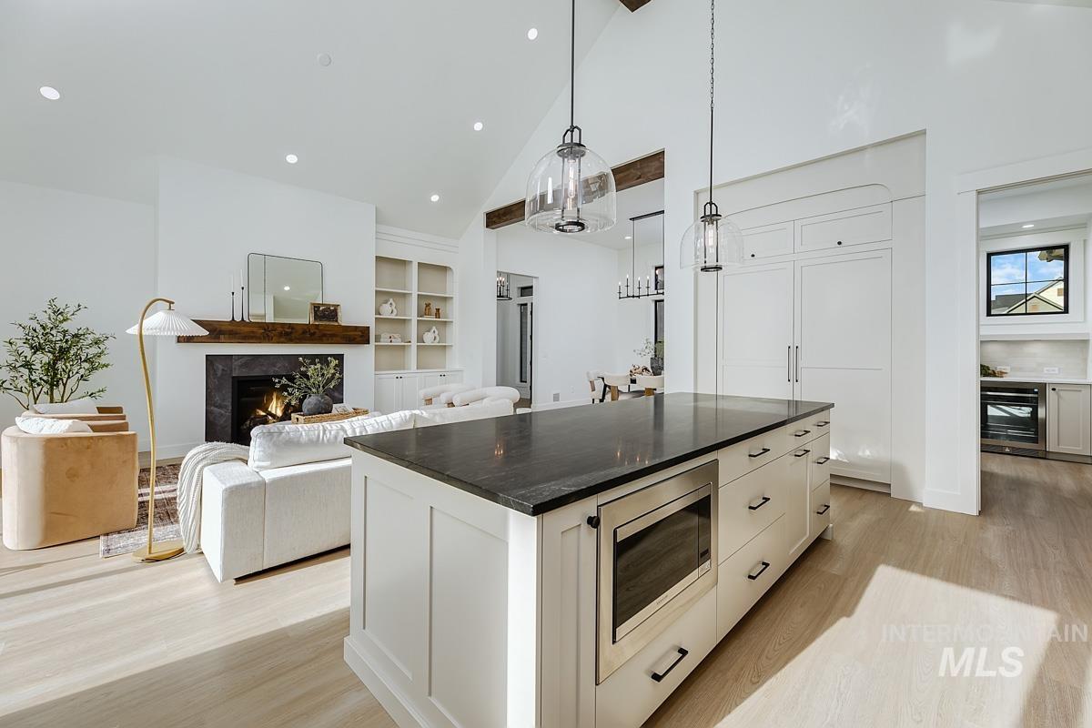 Kitchen with a kitchen island, high vaulted ceiling, open floor plan, decorative light fixtures, and stainless steel microwave