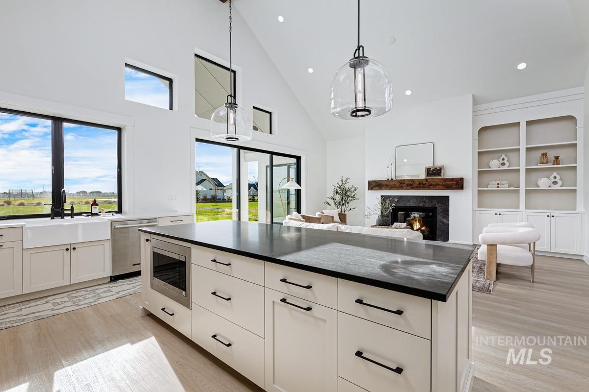 Kitchen featuring white cabinetry, decorative light fixtures, a high end fireplace, light wood-style floors, and a center island