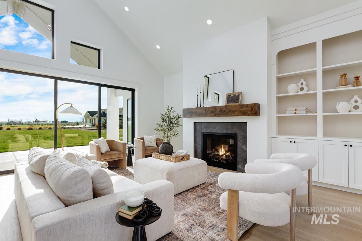 Living room featuring light wood-style flooring, a premium fireplace, high vaulted ceiling, recessed lighting, and built in features