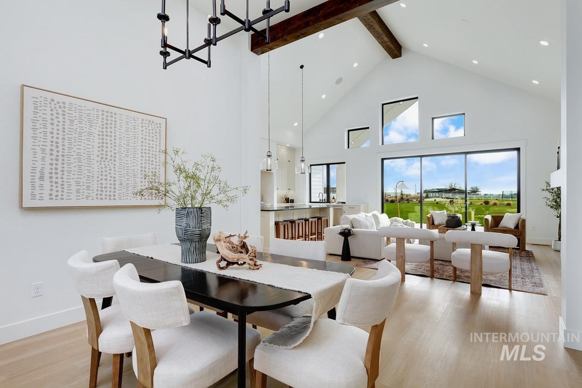 Dining space with high vaulted ceiling, light wood-type flooring, a chandelier, and beamed ceiling