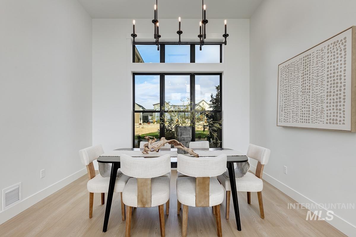 Dining area featuring light wood finished floors, a high ceiling, and a chandelier