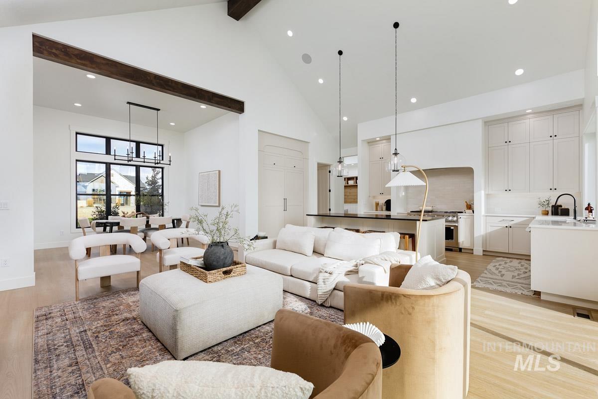 Living area featuring high vaulted ceiling, light wood finished floors, recessed lighting, beamed ceiling, and a chandelier