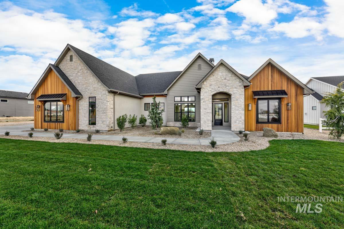 View of front facade with stone siding, a front lawn, and board and batten siding