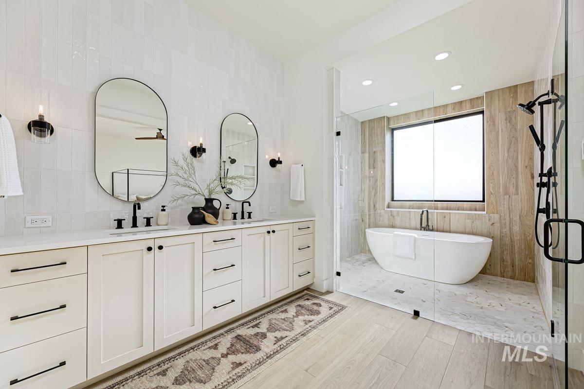 Full bath featuring a freestanding bath, tiled shower, tile walls, double vanity, and recessed lighting