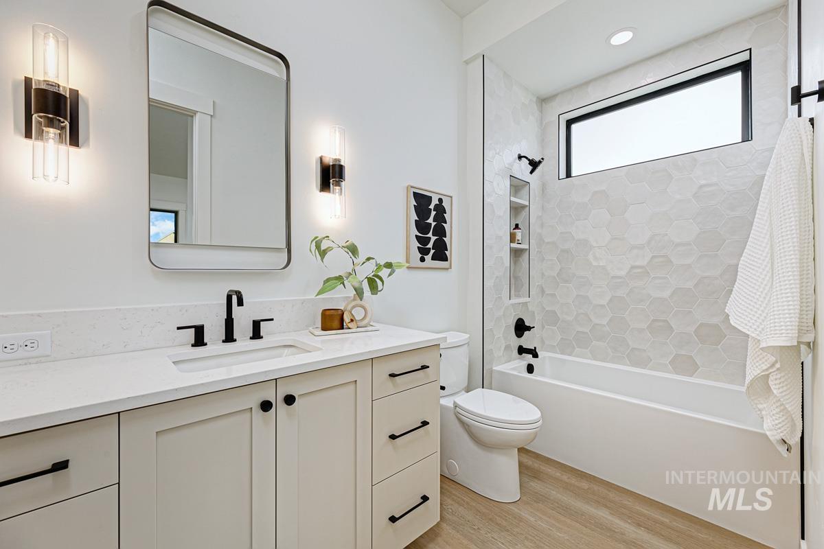 Bathroom featuring vanity, tub / shower combination, and light wood finished floors