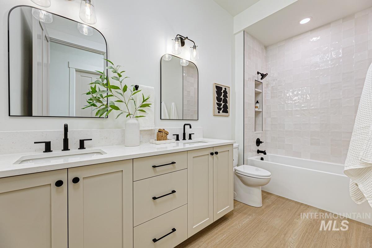 Bathroom with double vanity, light wood-style floors, shower / tub combo with curtain, and recessed lighting