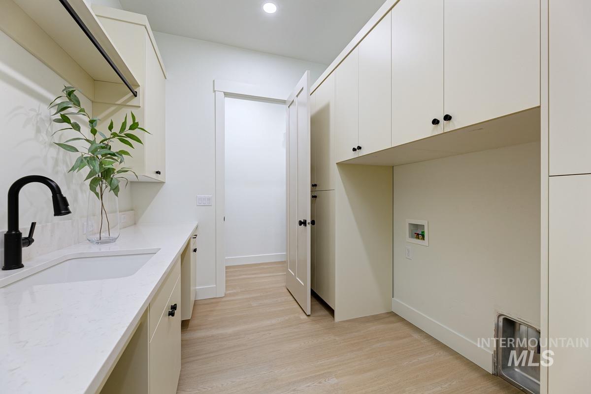 Washroom featuring light wood-style floors, cabinet space, hookup for a washing machine, and recessed lighting