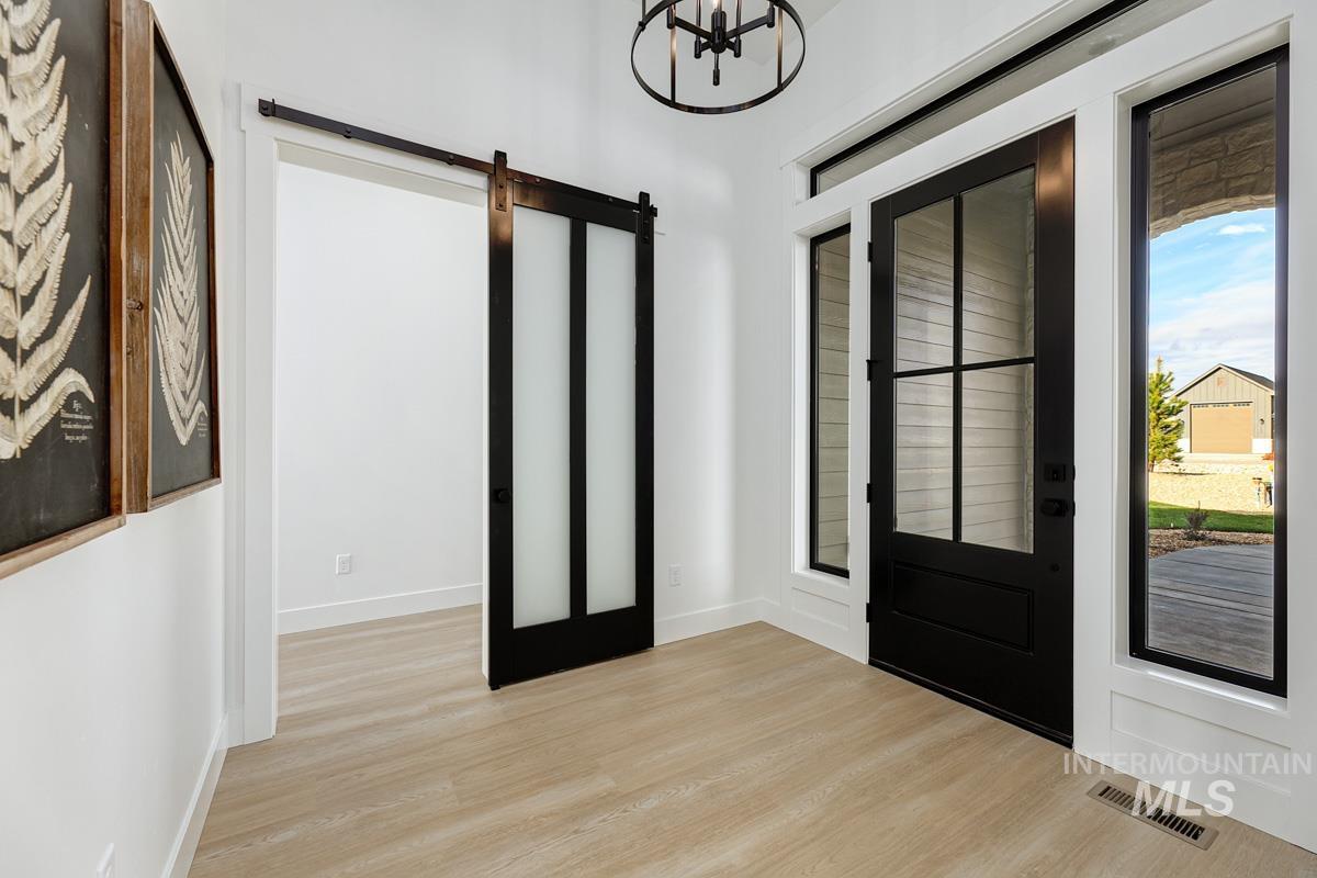 Foyer entrance featuring a barn door, light wood-type flooring, and a chandelier
