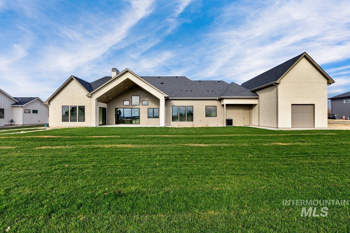 Rear view of property featuring a yard, a chimney, stucco siding, and a patio
