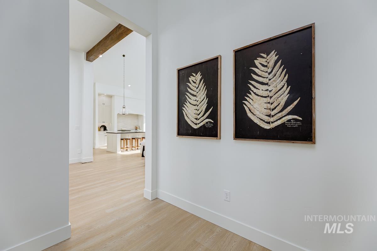 Corridor with beamed ceiling, light wood-type flooring, and high vaulted ceiling