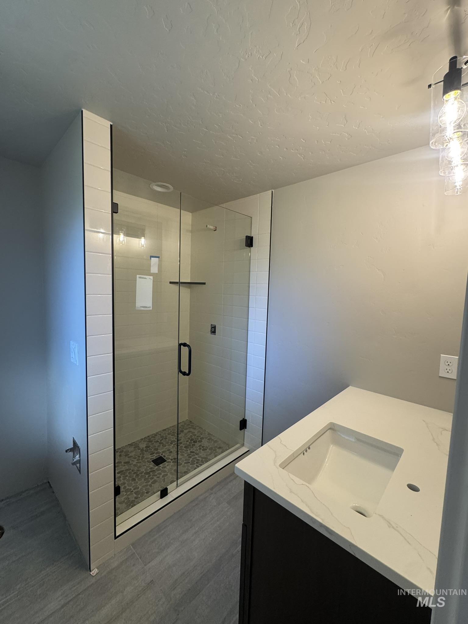 Full bathroom with vanity, a stall shower, and a textured ceiling