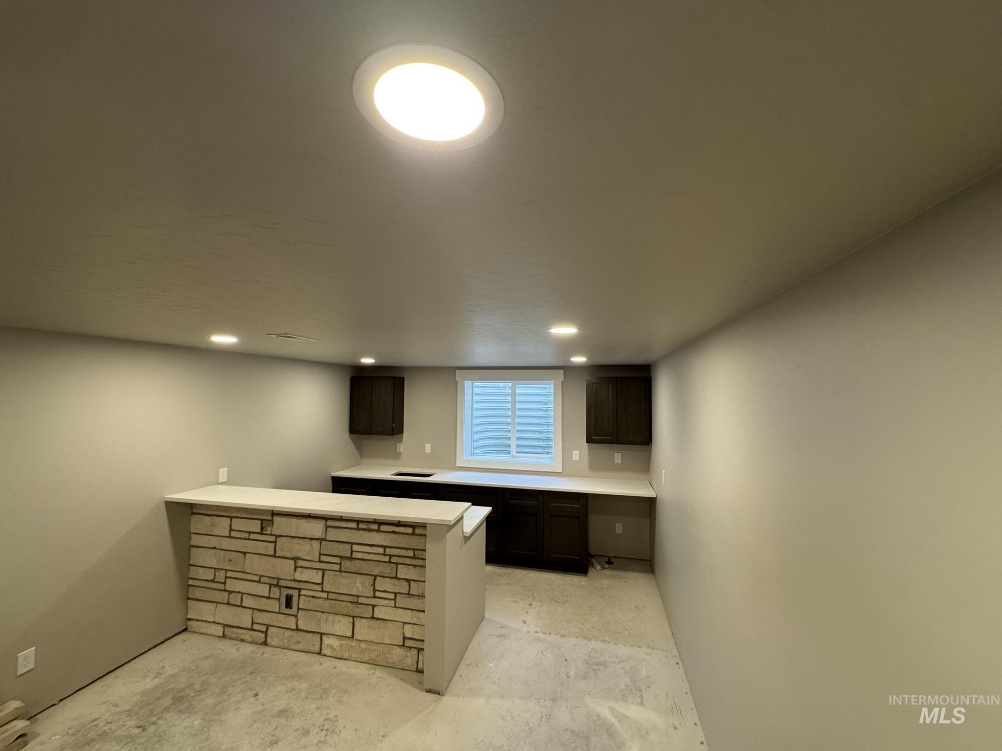 Bar featuring dark brown cabinetry, recessed lighting, and concrete floors