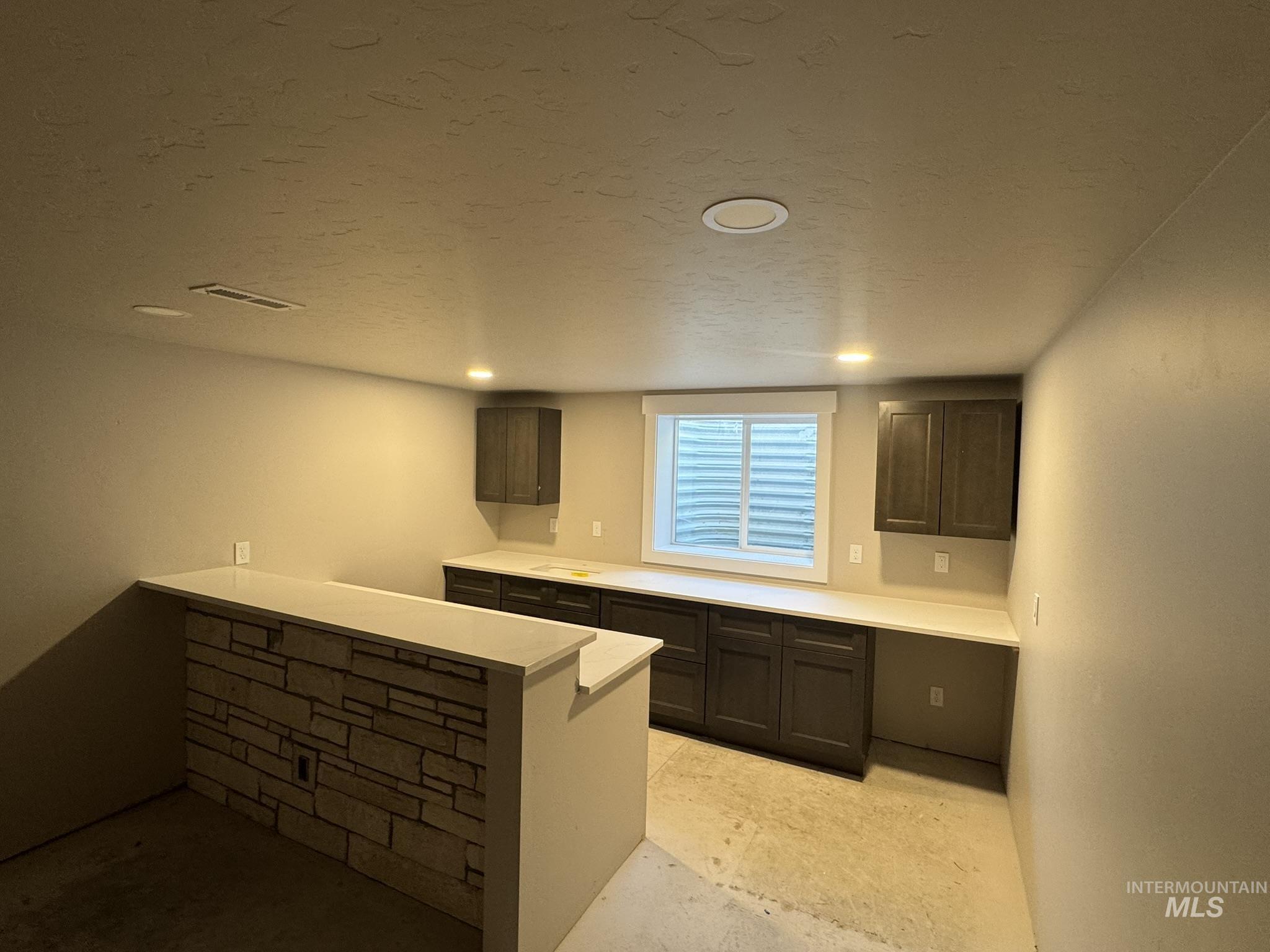 Kitchen featuring dark brown cabinetry, a textured ceiling, a peninsula, and recessed lighting