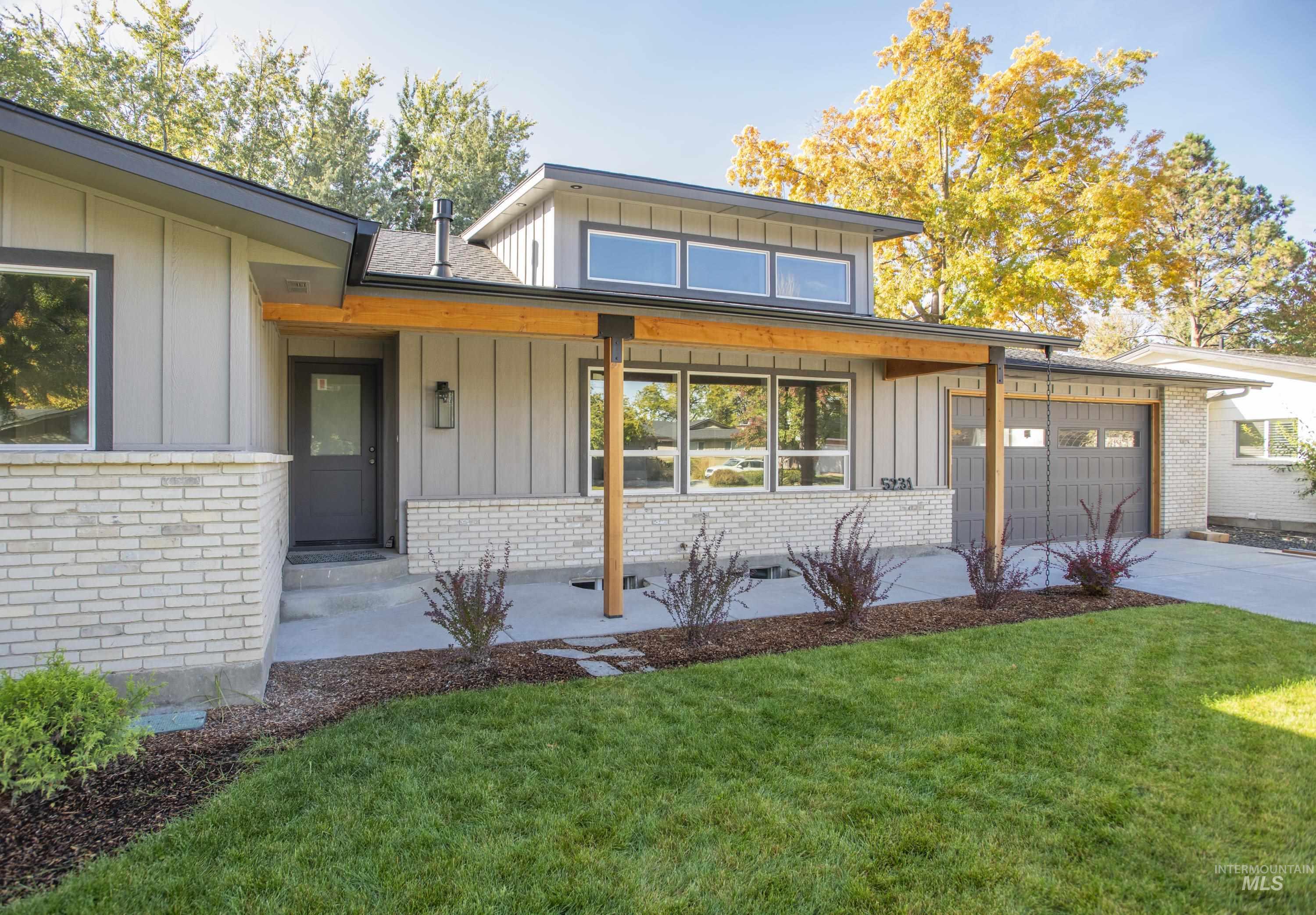 View of front of property featuring board and batten siding, covered porch, brick siding, and a front lawn
