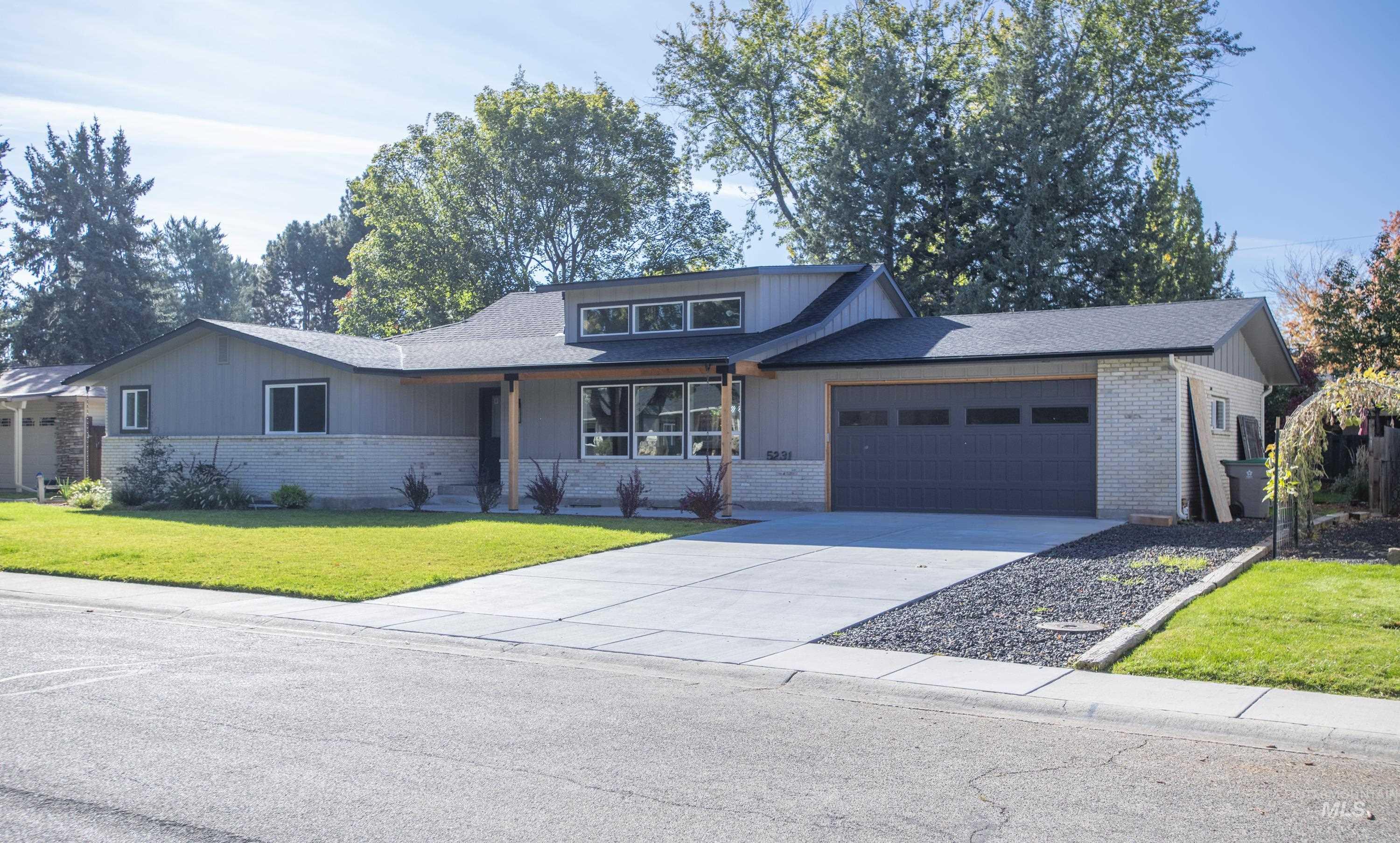 View of front of house featuring a front yard, concrete driveway, a garage, brick siding, and a shingled roof