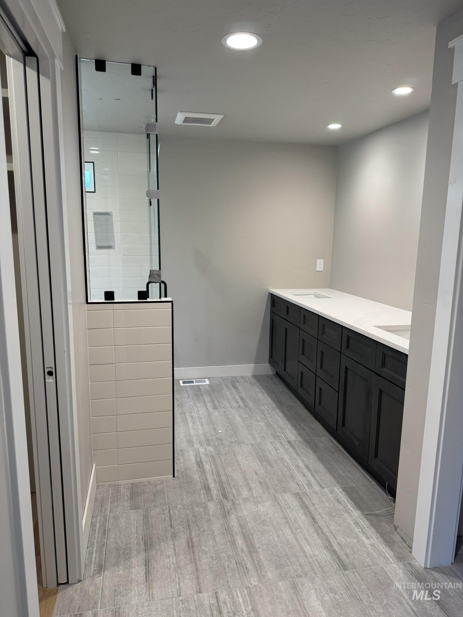 Bathroom with double vanity, recessed lighting, a shower stall, and light wood-type flooring