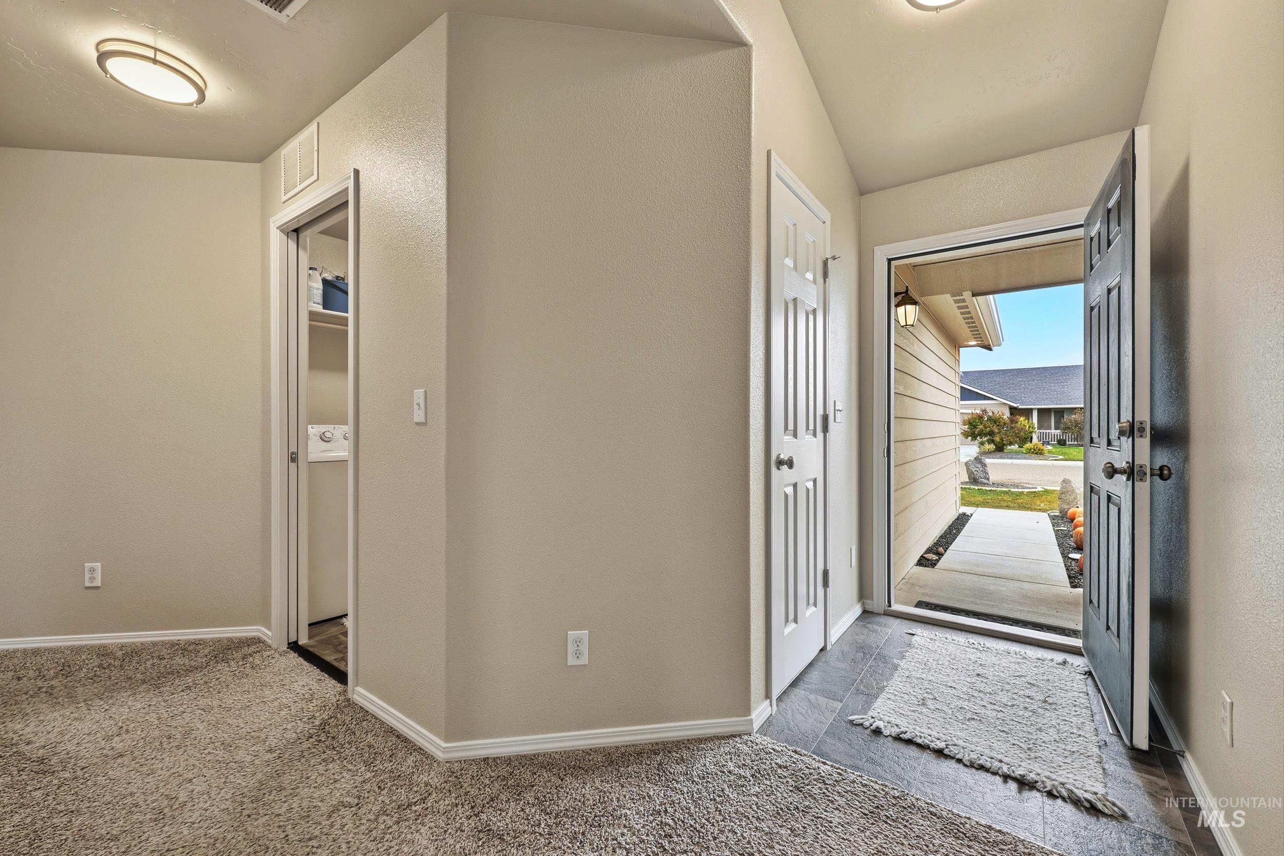 Foyer entrance with dark carpet and a textured wall