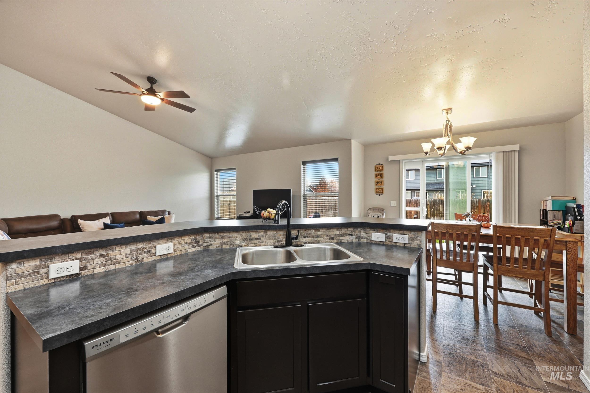 Kitchen featuring dark countertops, dishwasher, dark cabinetry, a chandelier, and pendant lighting