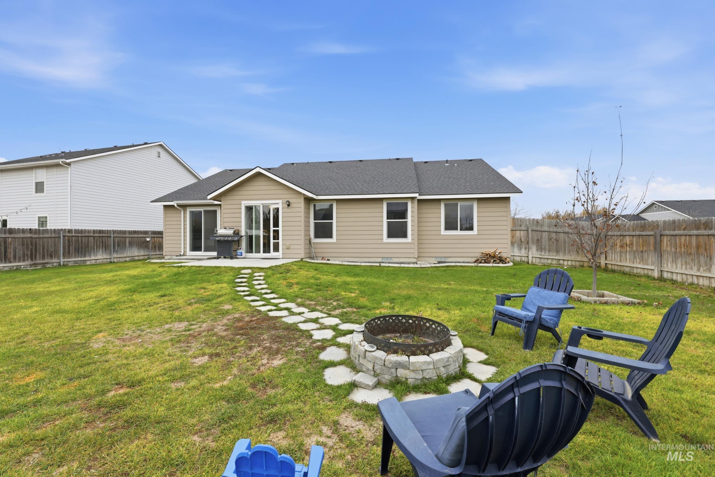 Rear view of house with an outdoor fire pit, a patio, a fenced backyard, and roof with shingles