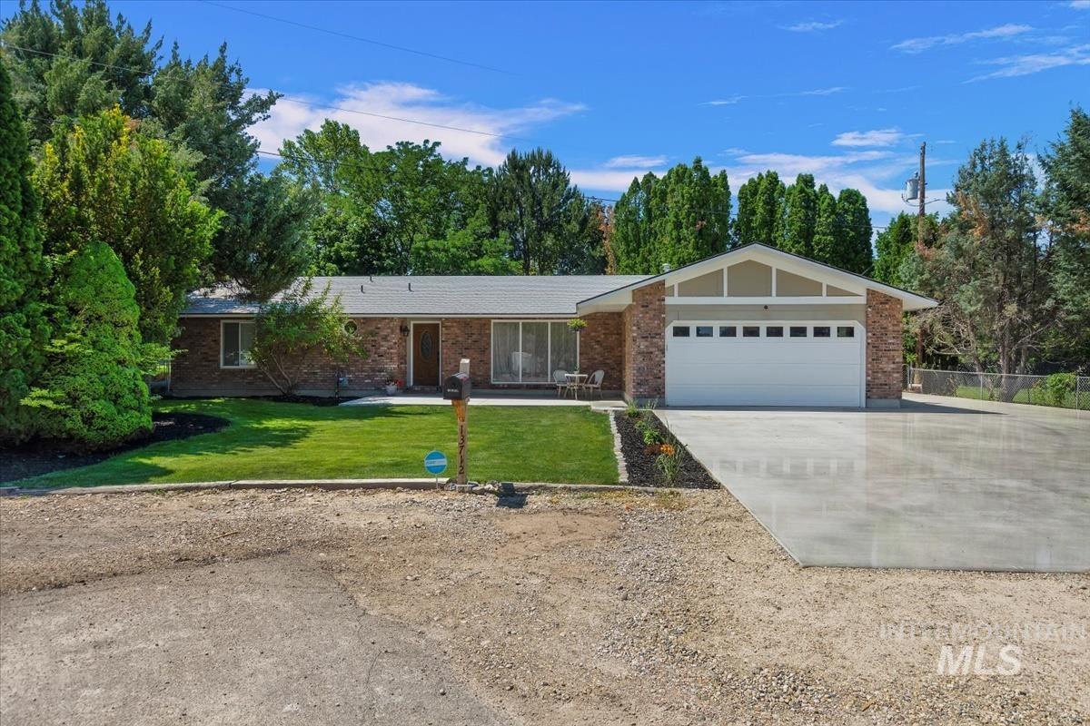 Single story home featuring a front lawn, driveway, brick siding, and a garage