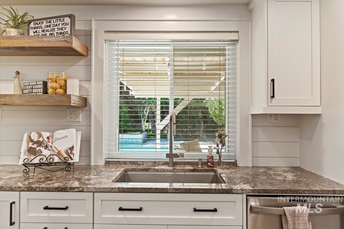 Kitchen featuring open shelves, white cabinets, dishwasher, and dark stone counters