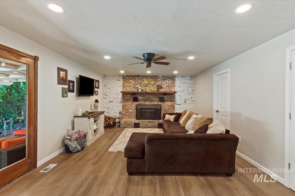 Living room featuring ceiling fan, wood finished floors, a textured ceiling, and recessed lighting
