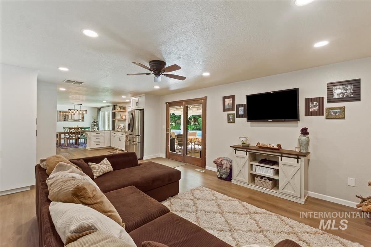 Living room with ceiling fan, recessed lighting, a textured ceiling, and light wood finished floors
