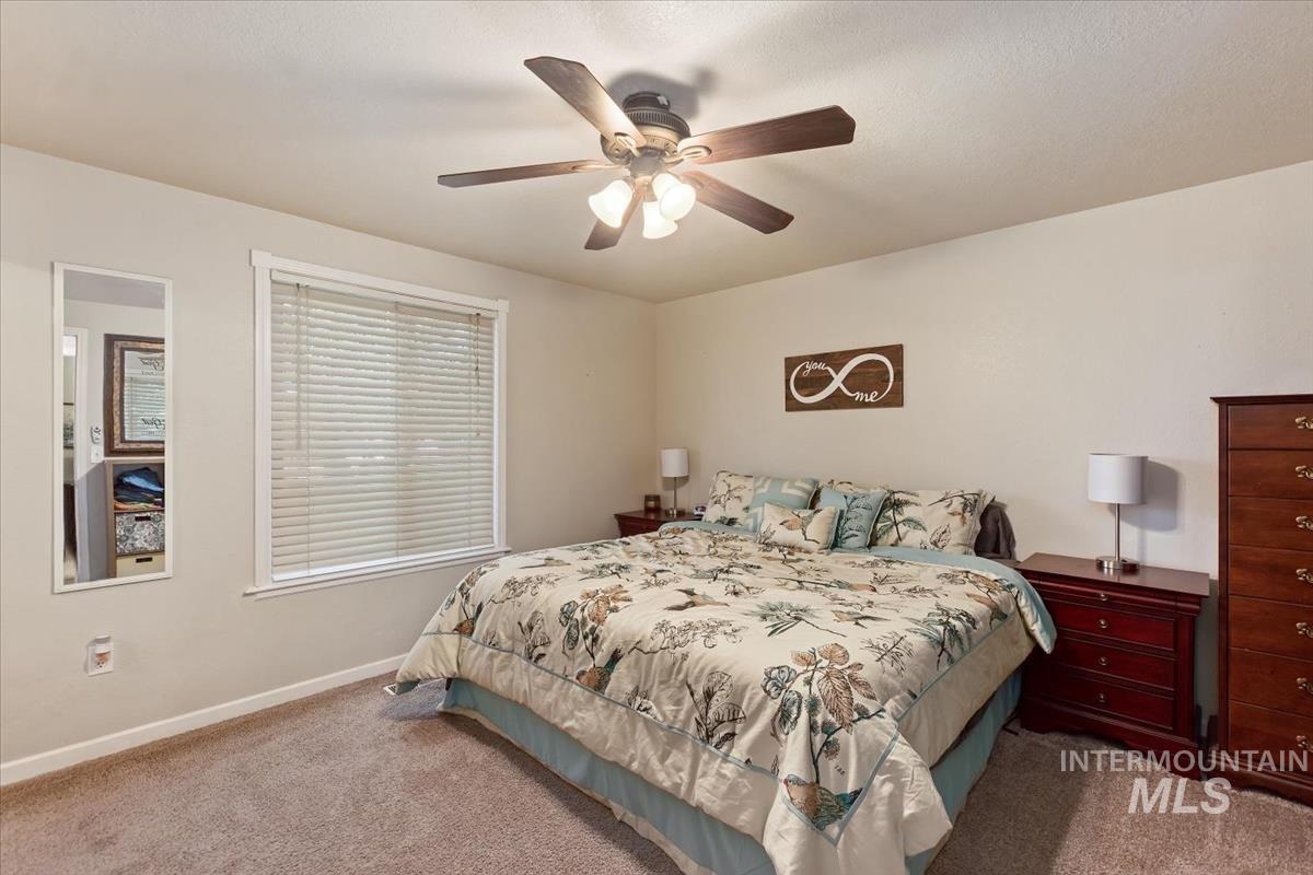 Carpeted bedroom with a ceiling fan and baseboards
