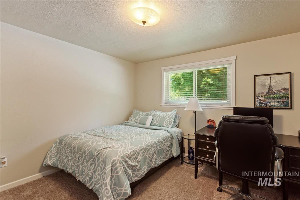 Carpeted bedroom with a textured ceiling and a desk