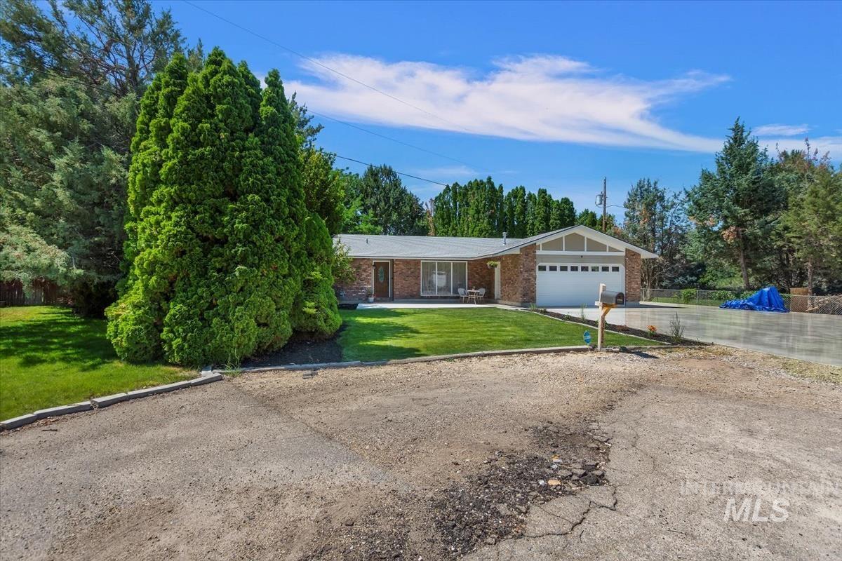 Ranch-style home with a front yard, concrete driveway, brick siding, an attached garage, and covered porch