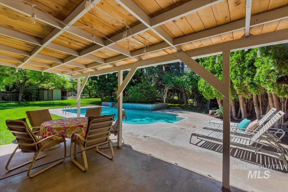 View of swimming pool with a shed, a patio, view of scattered trees, and a lawn
