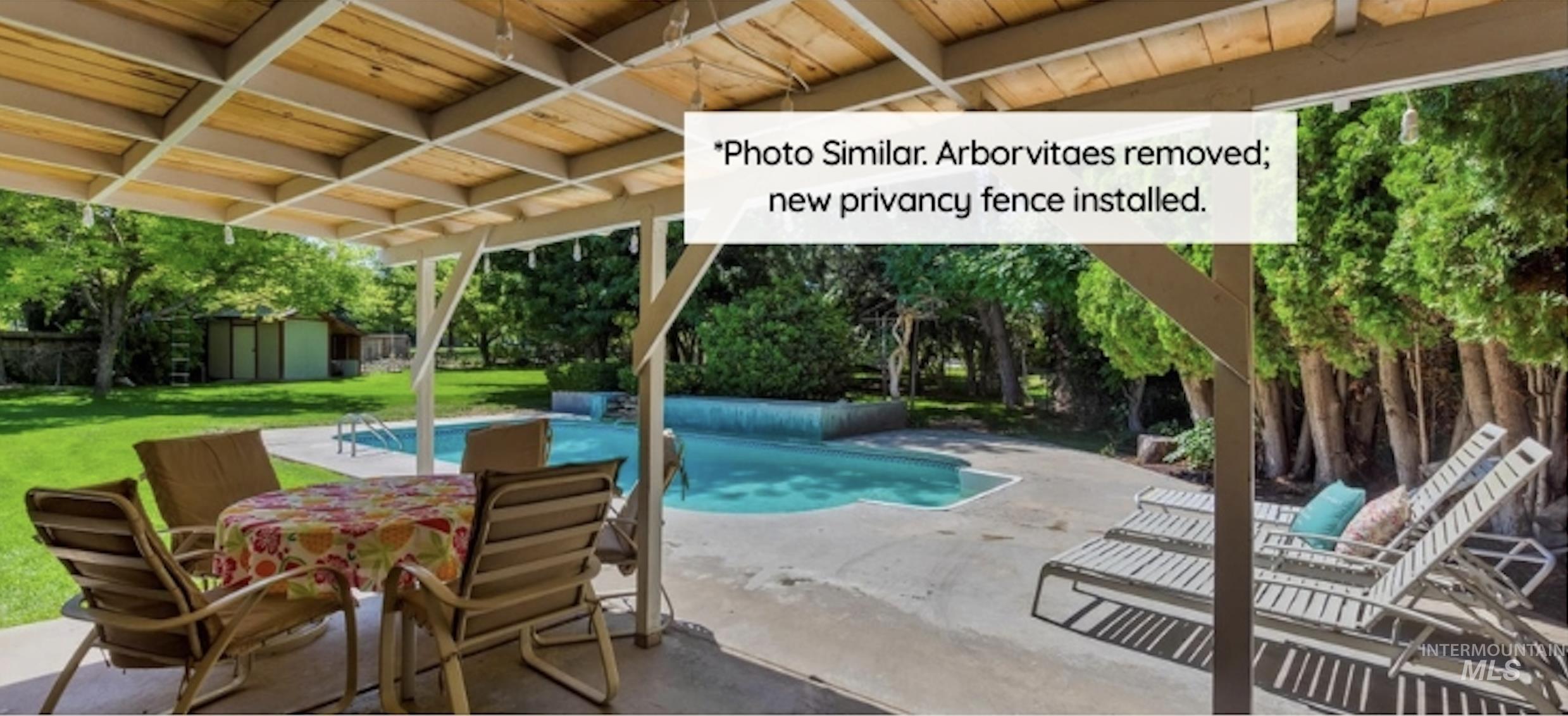 View of pool with a patio area, a yard, a storage unit, and view of scattered trees