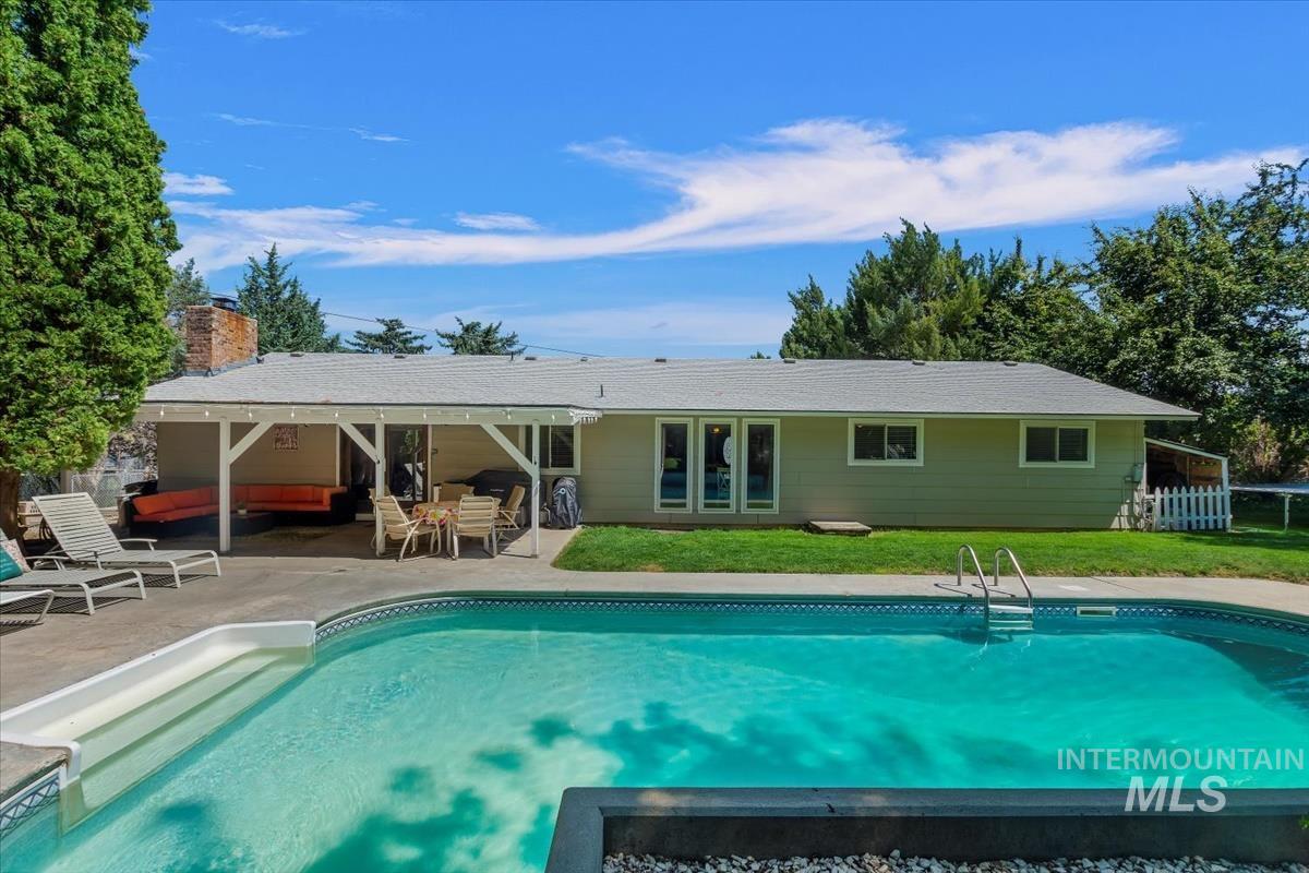 Rear view of property featuring a patio, an outdoor pool, a yard, and a chimney