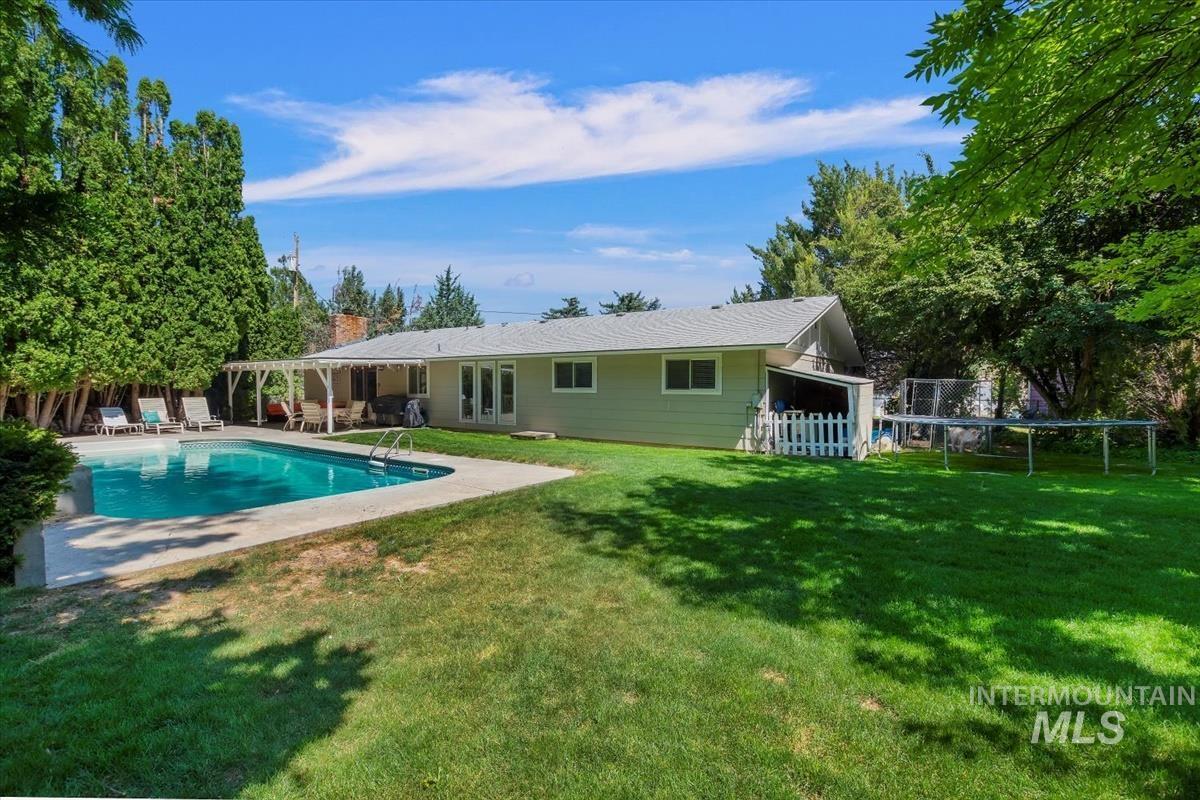 Back of house featuring a trampoline, a patio area, an outdoor pool, french doors, and a chimney