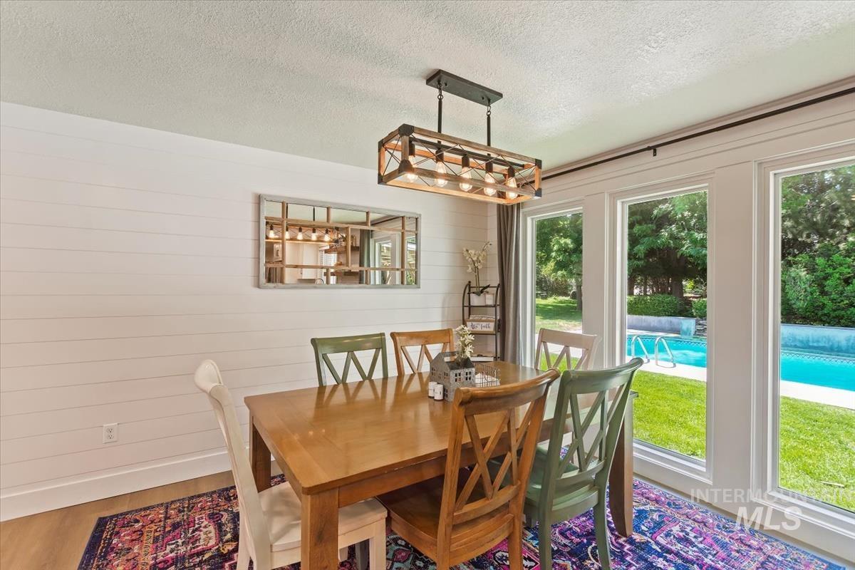 Dining space featuring a textured ceiling, wood finished floors, and wood walls