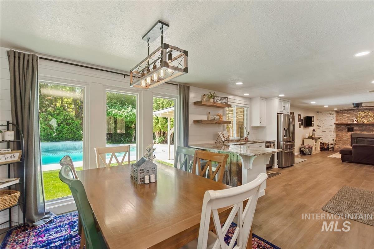 Dining room featuring a textured ceiling, light wood-type flooring, and a brick fireplace