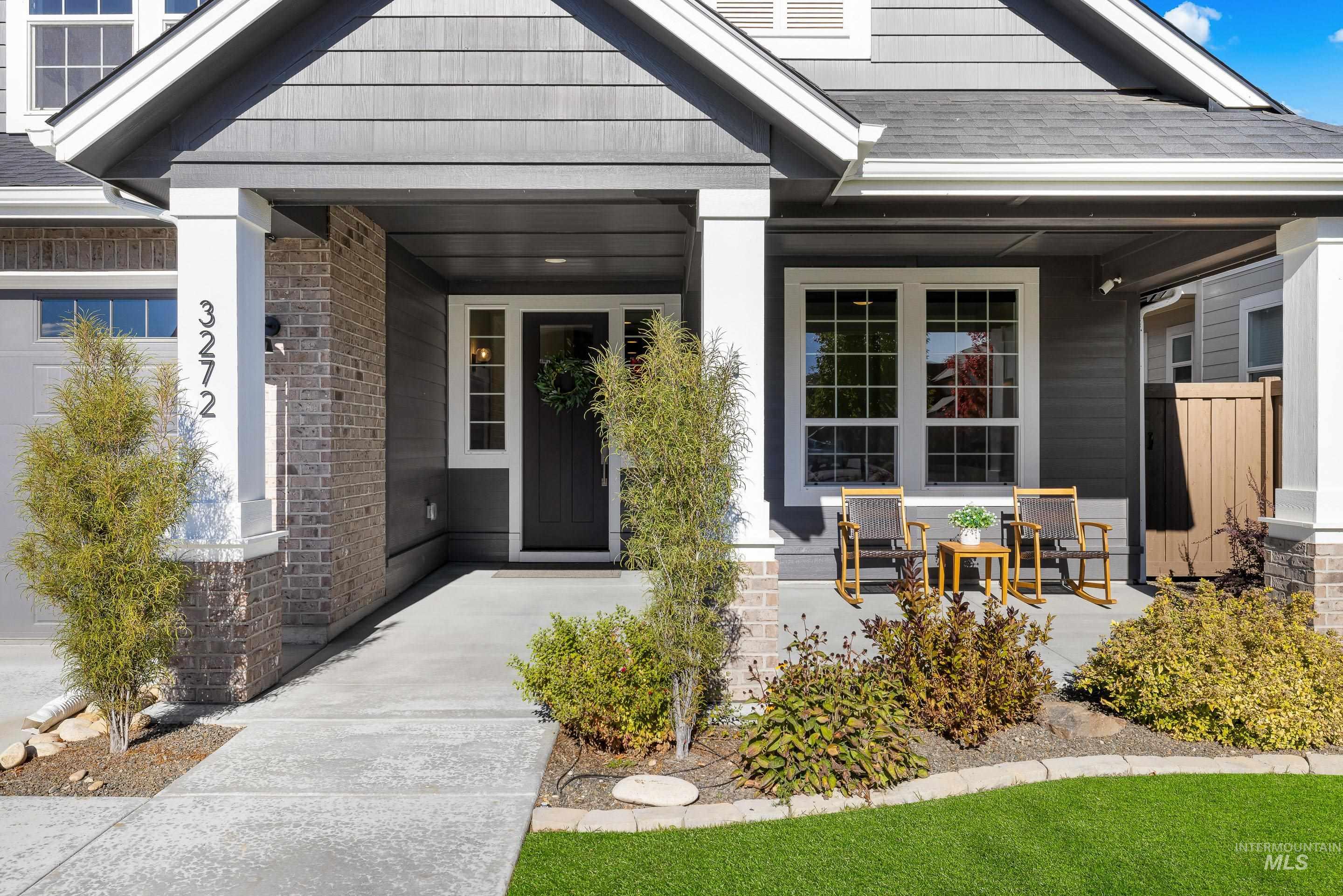 Property entrance featuring brick siding, covered porch, a garage, and roof with shingles